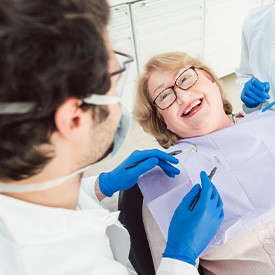 Woman with glasses smiling while looking at dentist
