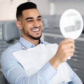 Man smiling at reflection in mirror in treatment chair