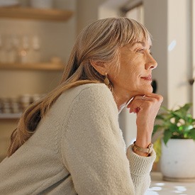 Senior woman smiling while looking out the window at home