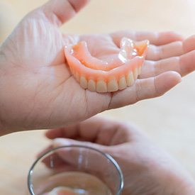 A hand holding a denture