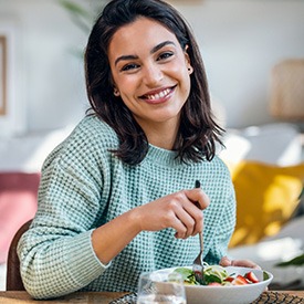 Woman smiling while eating lunch at home