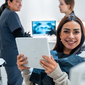 Patient smiling while holding mirror in treatment chair