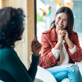 Two women chatting and smiling at work desk