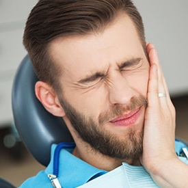 Man holding cheek in pain