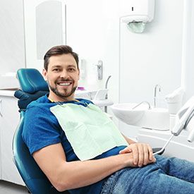  Man smiling in dental chair while wearing a blue shirt