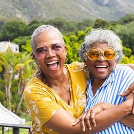 Two friends smiling and embracing outdoors