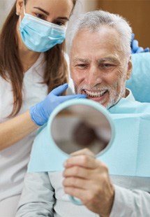 patient smiling while looking in dental mirror 