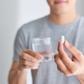 Man preparing to swallow oral conscious sedation pill