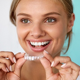 Woman smiling while holding a teeth whitening tray