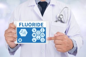 dentist holding sign with fluoride written