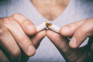 man breaking cigarette in his hands