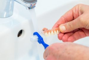 Man whitening his dentures in a sink. 