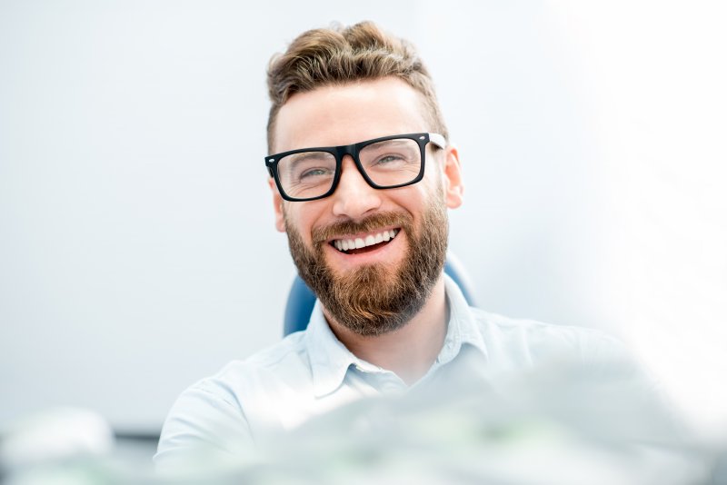 patient who just underwent cosmetic dentistry smiling in dental chair