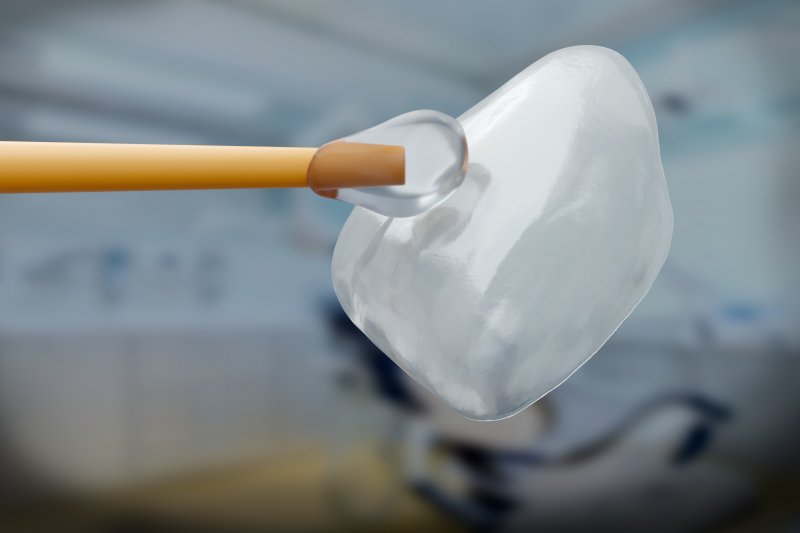 A closeup of a dental veneer and an applicator