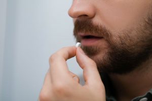 Man preparing to swallow pill for oral conscious sedation