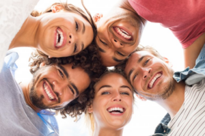 A group of friends standing in a circle and smiling down at the camera 