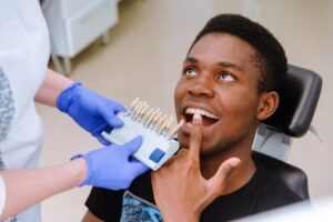 Dentist holding up veneers to patient in dentist's chair.