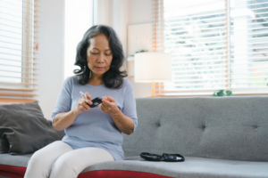 a woman sitting on a couch measuring her blood sugar