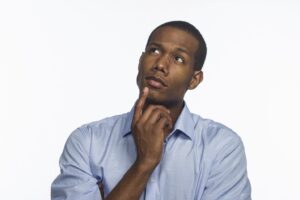 Man with unsure expression, finger on his chin and looking upward.
