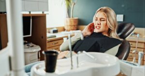 Dental patient wincing in pain from tooth sensitivity.
